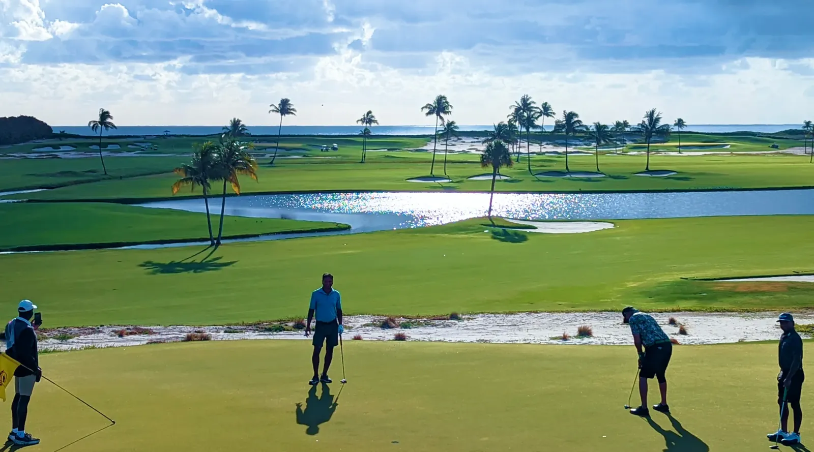 Golfers sharing a round on a green beside the ocean